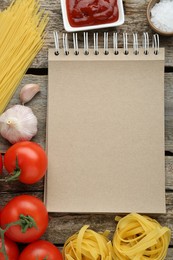 Photo of Blank recipe book and different ingredients on wooden table, flat lay. Space for text