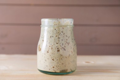 Photo of Sourdough starter in glass jar on wooden table