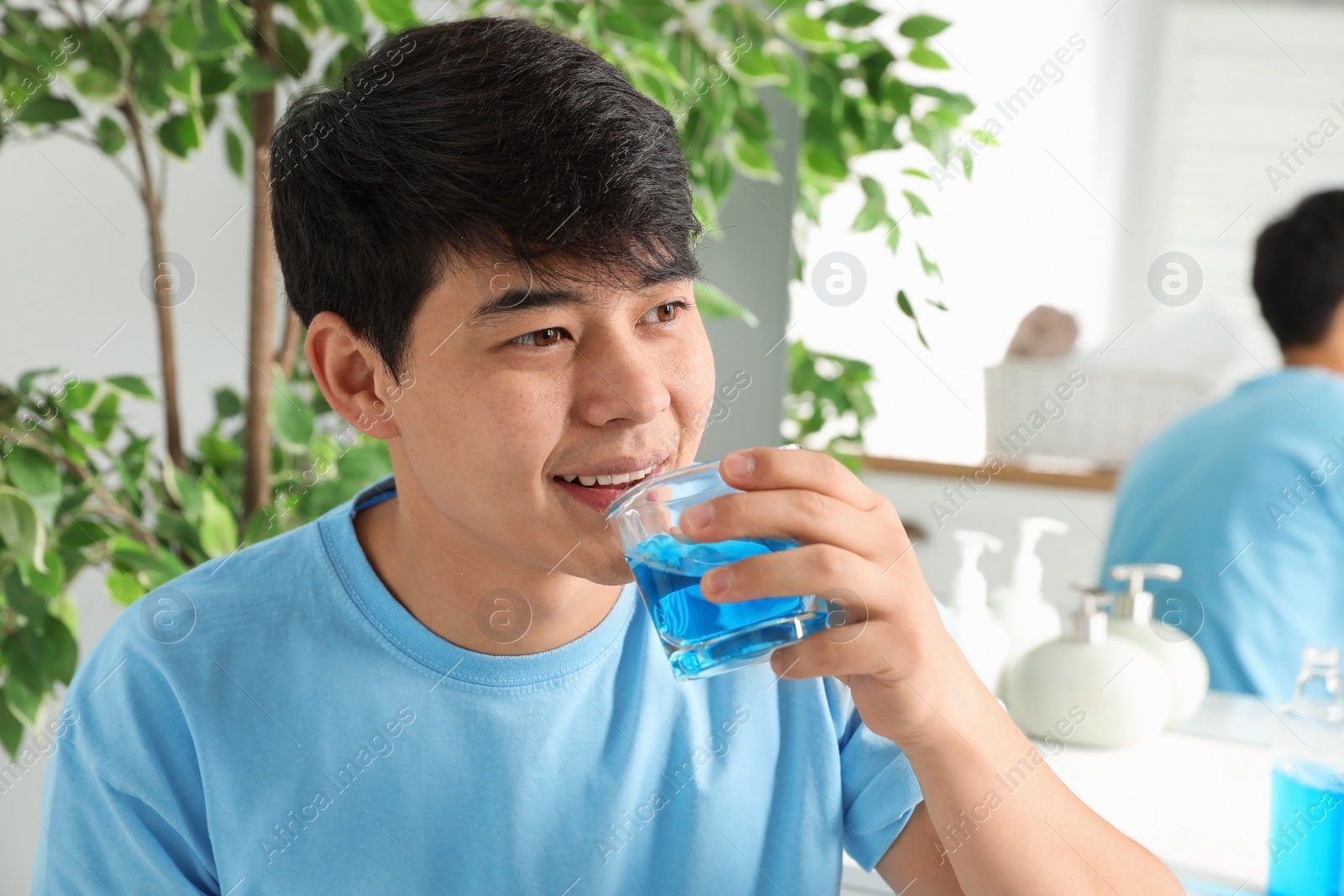 Photo of Man rinsing mouth with mouthwash in bathroom. Teeth care