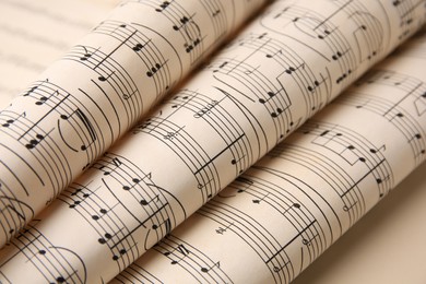 Rolled sheets with music notes on light background, closeup
