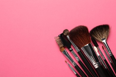 Set of makeup brushes on pink background, flat lay. Space for text
