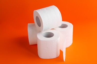 Soft toilet paper rolls on orange background, closeup