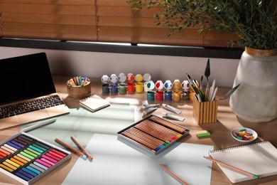 Artist's workplace with soft pastels, laptop and drawing pencils on table