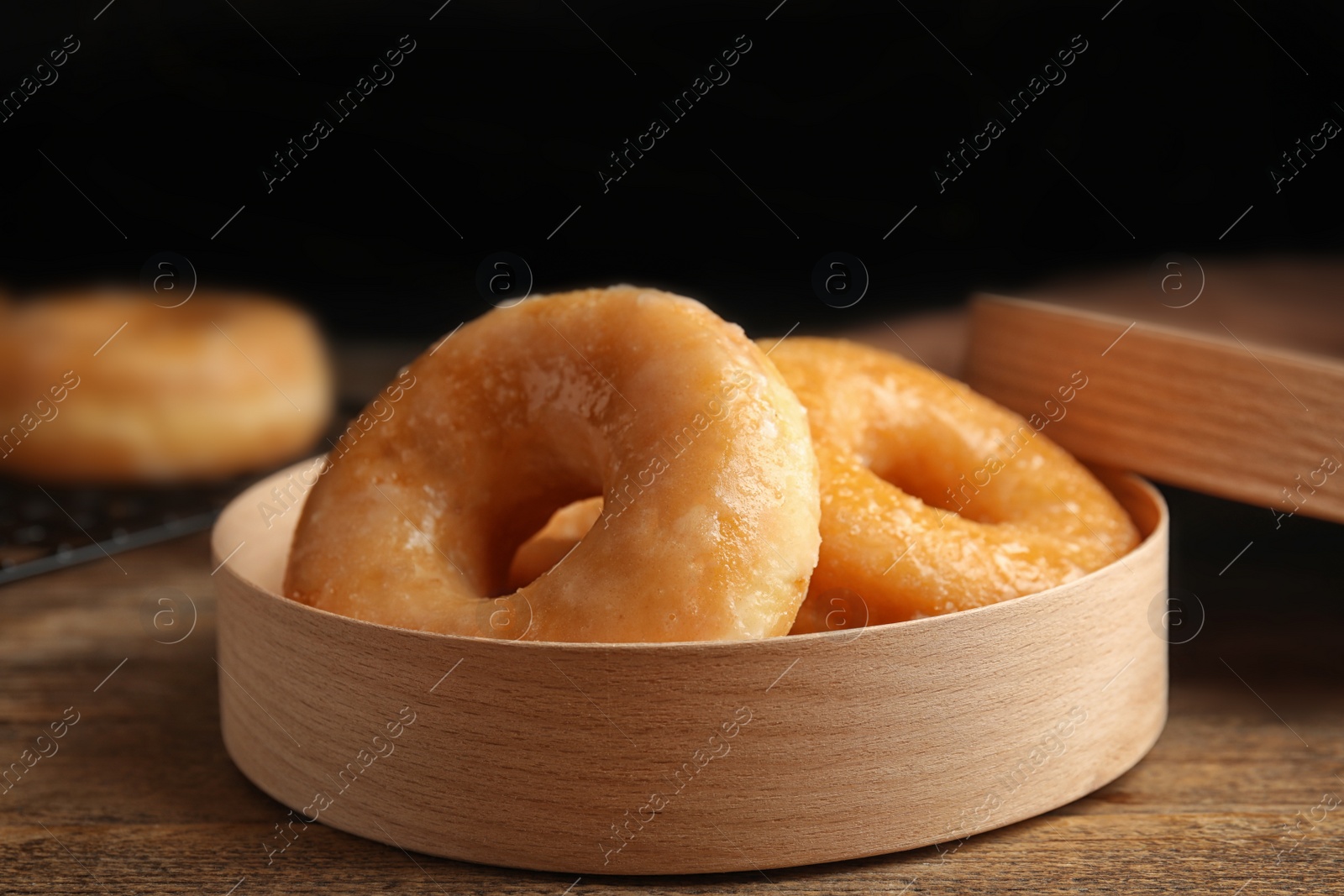 Photo of Delicious donuts in box on wooden table, closeup