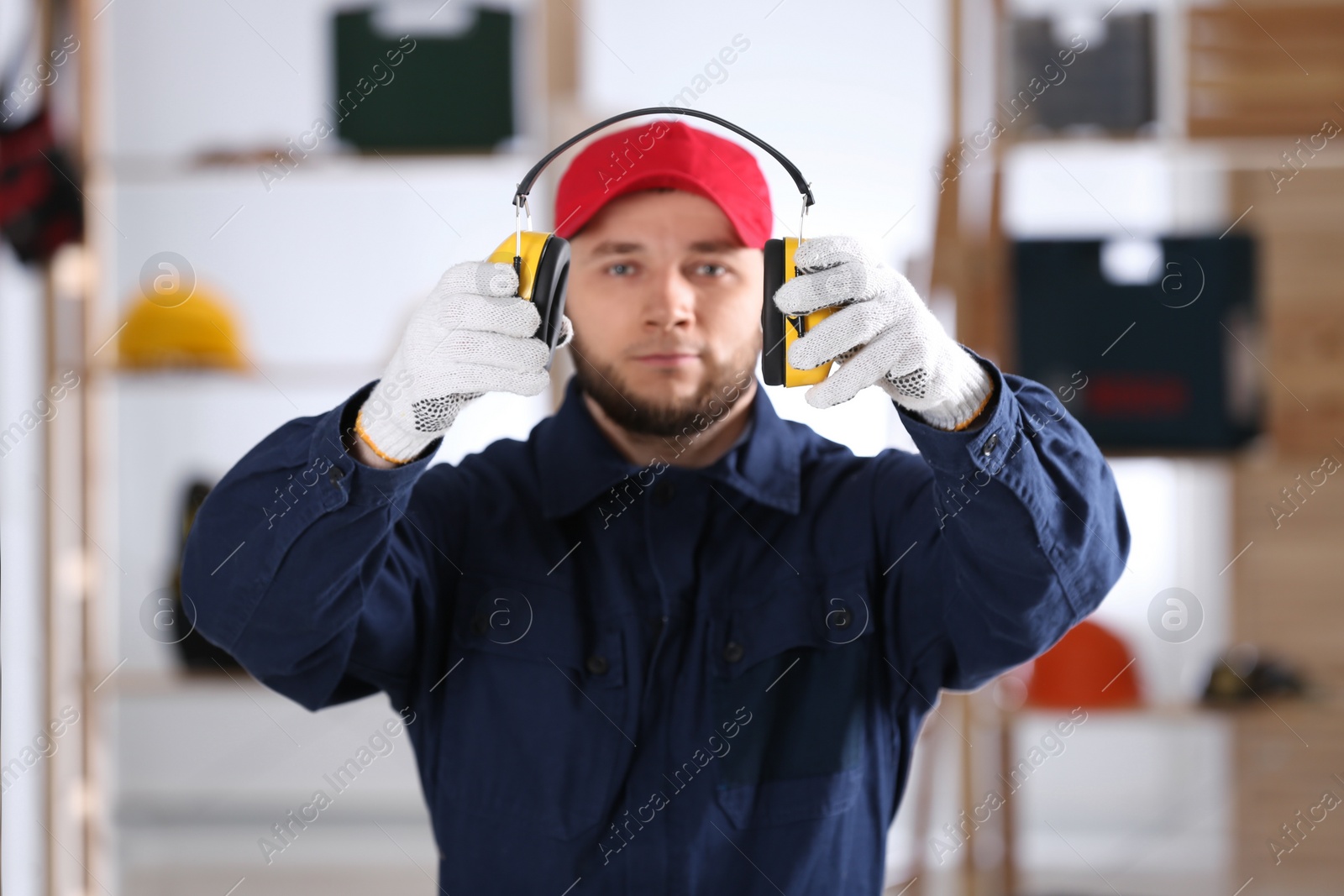 Photo of Worker holding safety headphones indoors, focus on hands. Hearing protection device