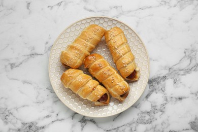 Delicious sausage rolls on white marble table, top view