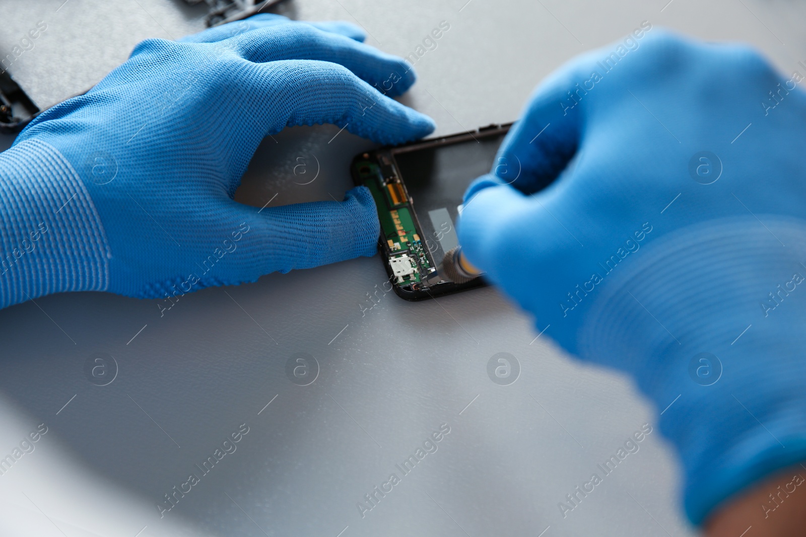 Photo of Technician repairing mobile phone at table, closeup