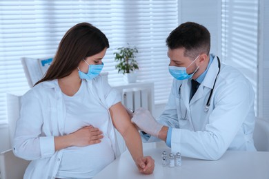 Doctor vaccinating pregnant woman against Covid-19 in clinic