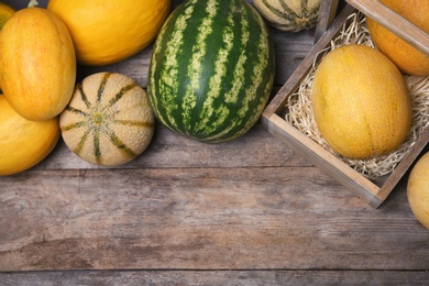 Photo of Ripe melons and watermelon on wooden background, flat lay. Space for text