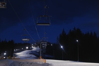 Photo of Beautiful mountain landscape with chairlift and piste at night. Winter vacation