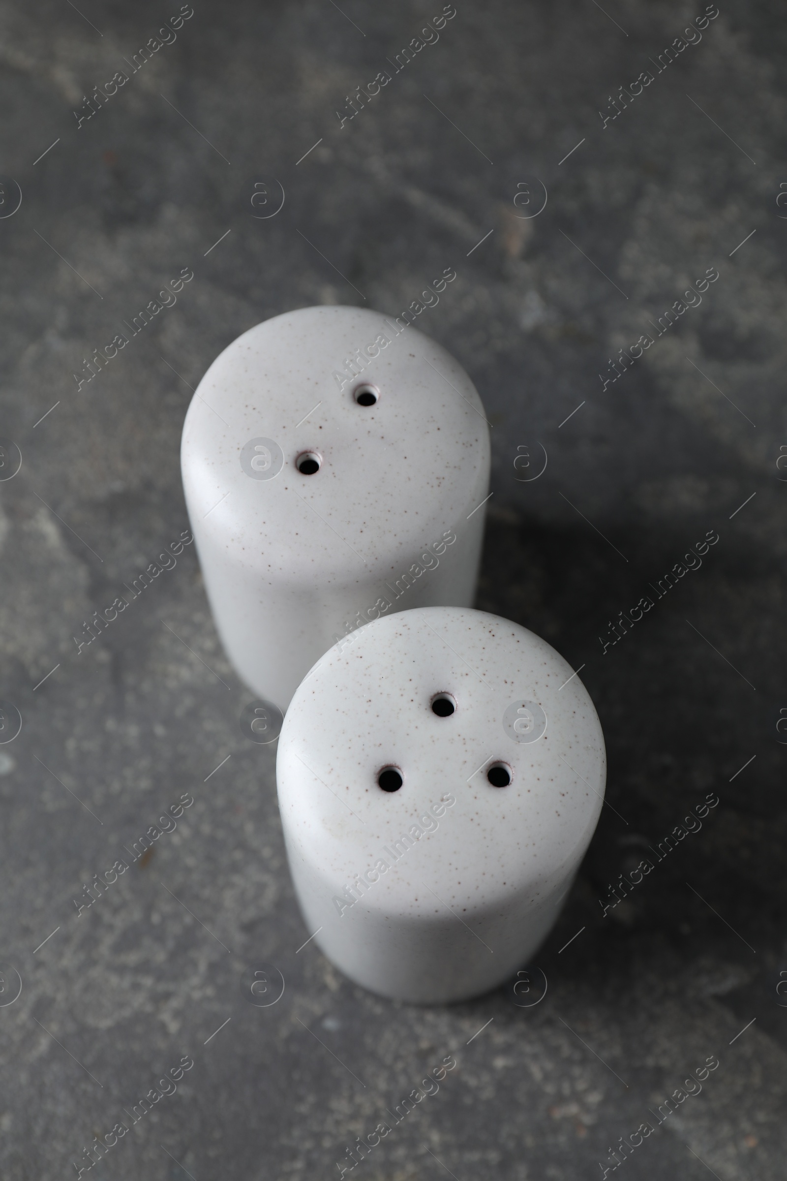 Photo of Salt and pepper shakers on dark textured table, above view