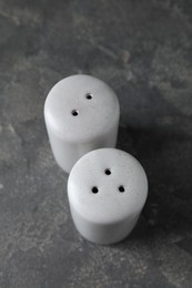 Photo of Salt and pepper shakers on dark textured table, above view