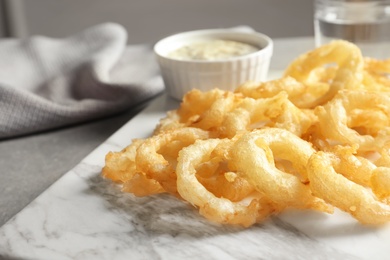 Closeup view of delicious golden breaded and deep fried crispy onion rings on marble board