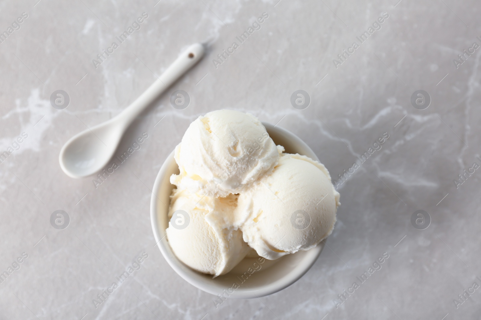 Photo of Bowl with tasty vanilla ice cream on light background