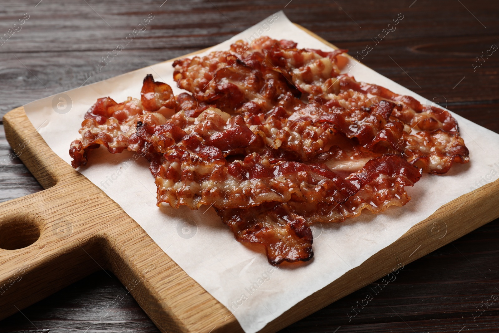 Photo of Slices of tasty fried bacon on wooden table