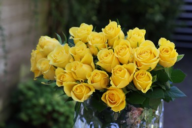 Beautiful bouquet of yellow roses in glass vase outdoors, closeup