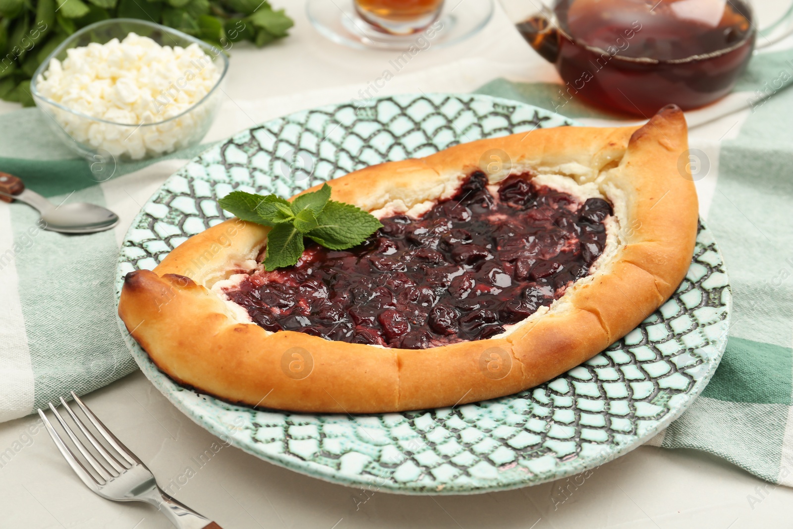 Photo of Delicious sweet cottage cheese pastry with cherry jam on white table