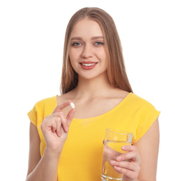 Photo of Young woman with vitamin pill and glass of water on white background