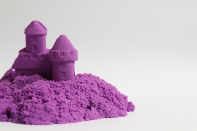 Photo of Castle made of purple kinetic sand on white background. Space for text