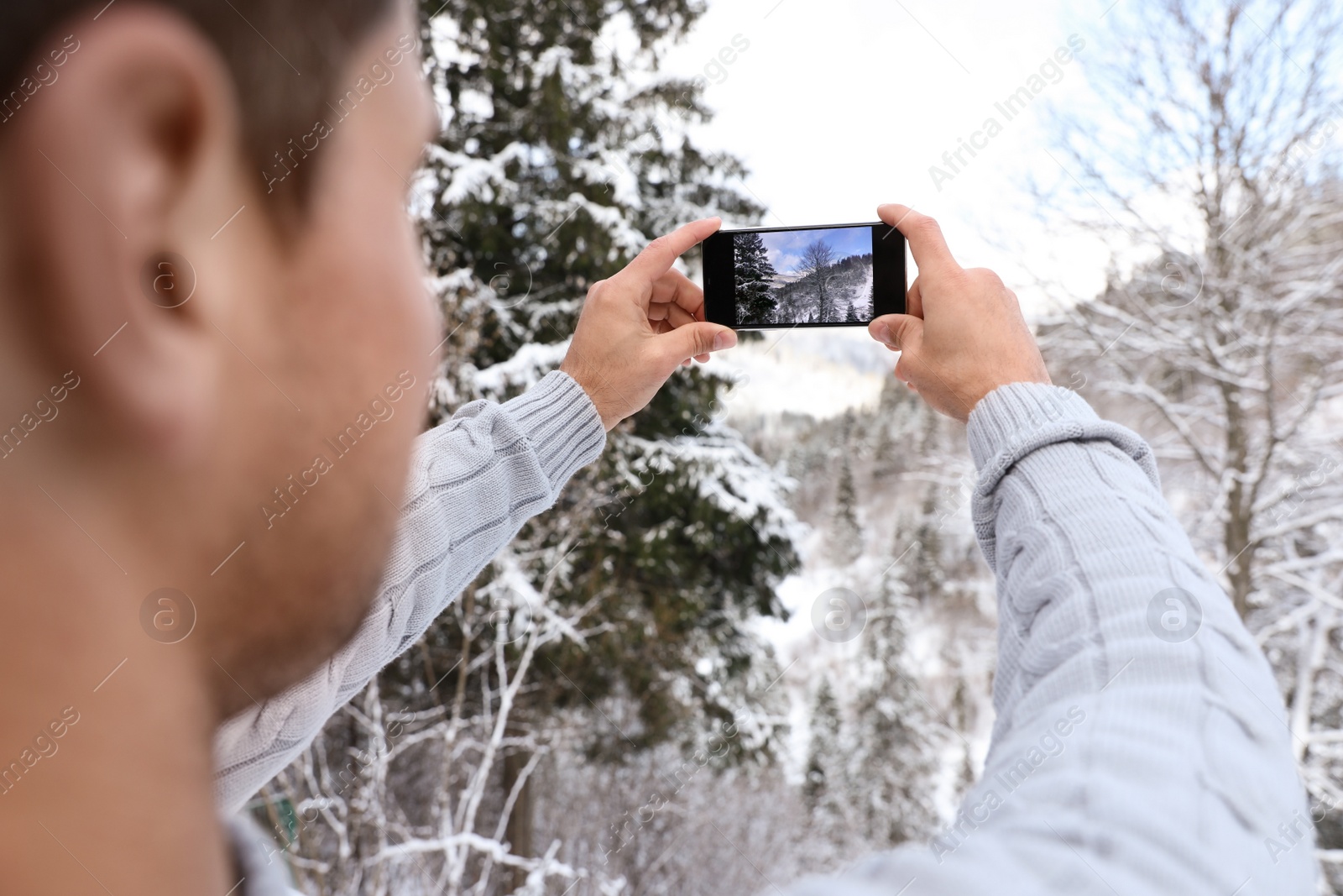 Photo of Man taking picture of snowy tree outdoors, closeup