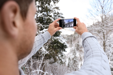Man taking picture of snowy tree outdoors, closeup