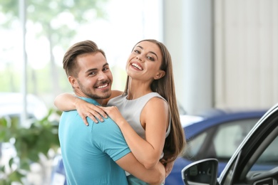 Happy couple buying new car in salon