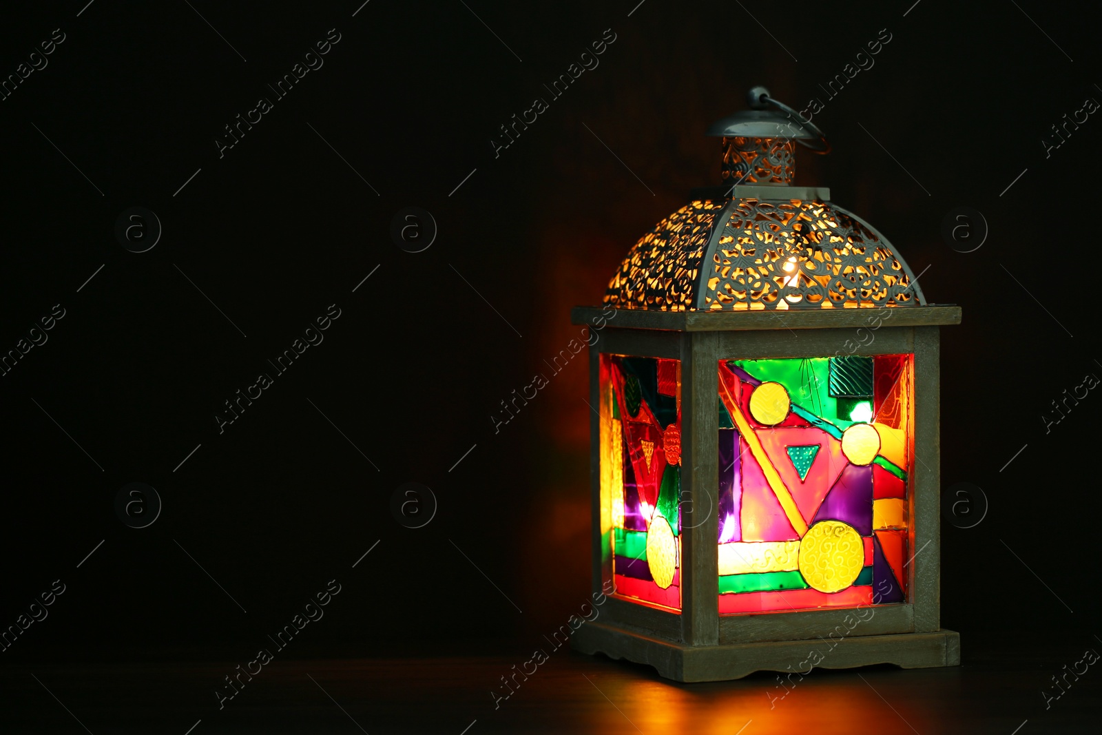 Photo of Decorative Arabic lantern on table against dark background. Space for text