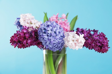 Beautiful hyacinths in glass vase on color background. Spring flowers