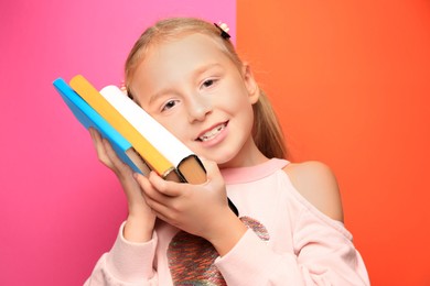 Photo of Cute little girl with books on colorful background