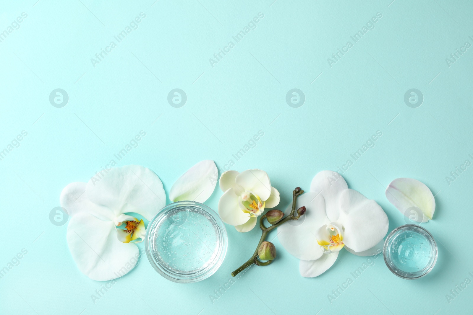 Photo of Flat lay composition with cosmetic gel and beautiful flowers on light blue background. Space for text