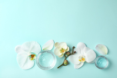 Photo of Flat lay composition with cosmetic gel and beautiful flowers on light blue background. Space for text