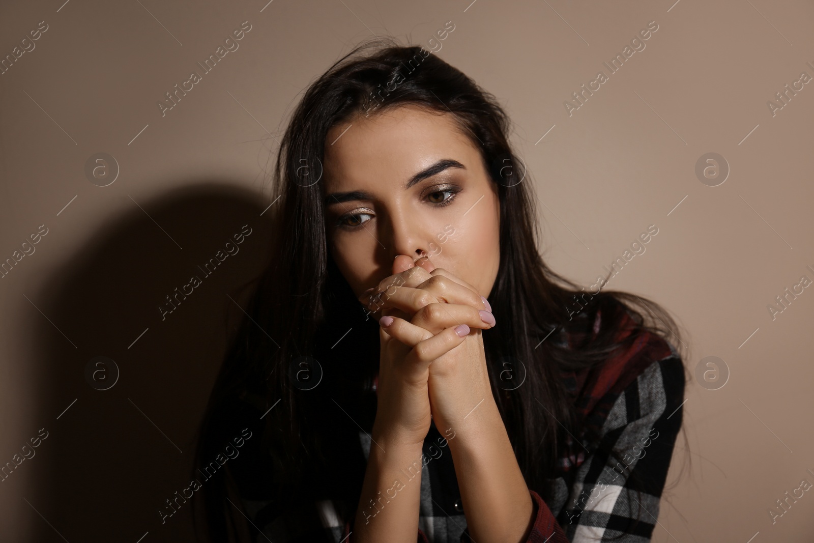 Photo of Abused young woman near beige wall. Domestic violence concept