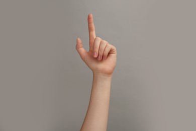 Photo of Woman showing index finger on grey background, closeup