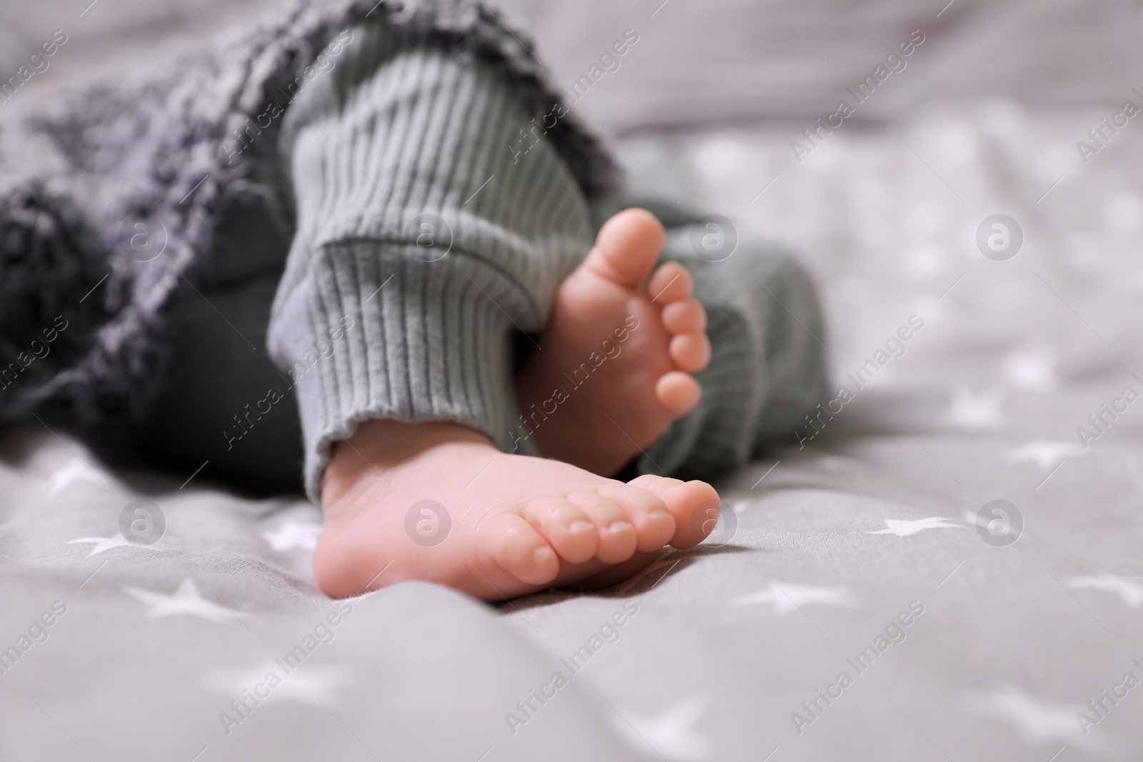 Photo of Cute newborn baby lying on bed, closeup of legs. Space for text