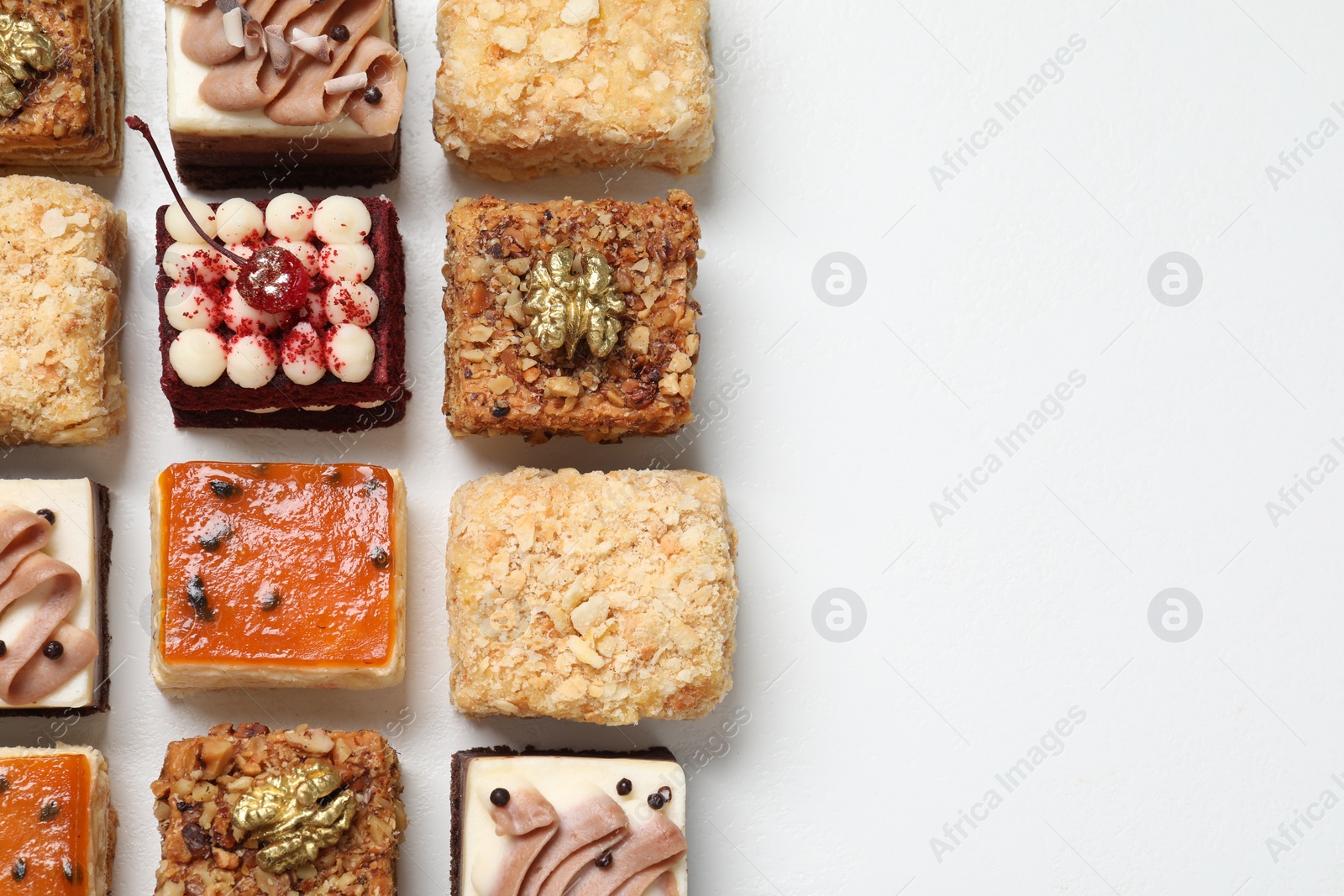 Photo of Pieces of different delicious cakes on white table, flat lay. Space for text