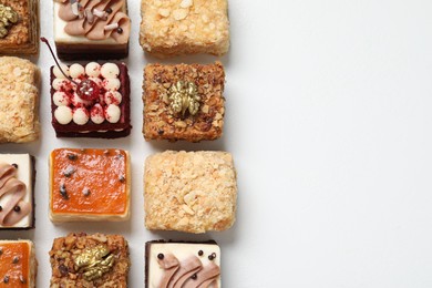 Photo of Pieces of different delicious cakes on white table, flat lay. Space for text