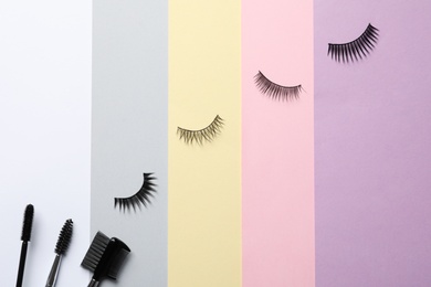 Photo of False eyelashes and brushes on color background, flat lay