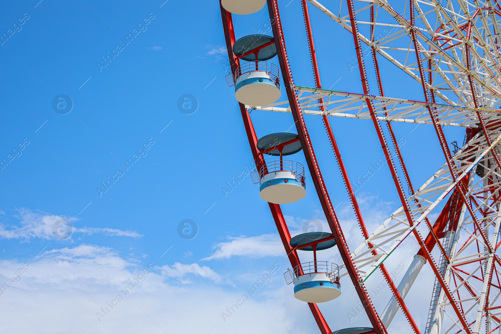 Photo of Beautiful large Ferris wheel against blue sky with clouds, closeup