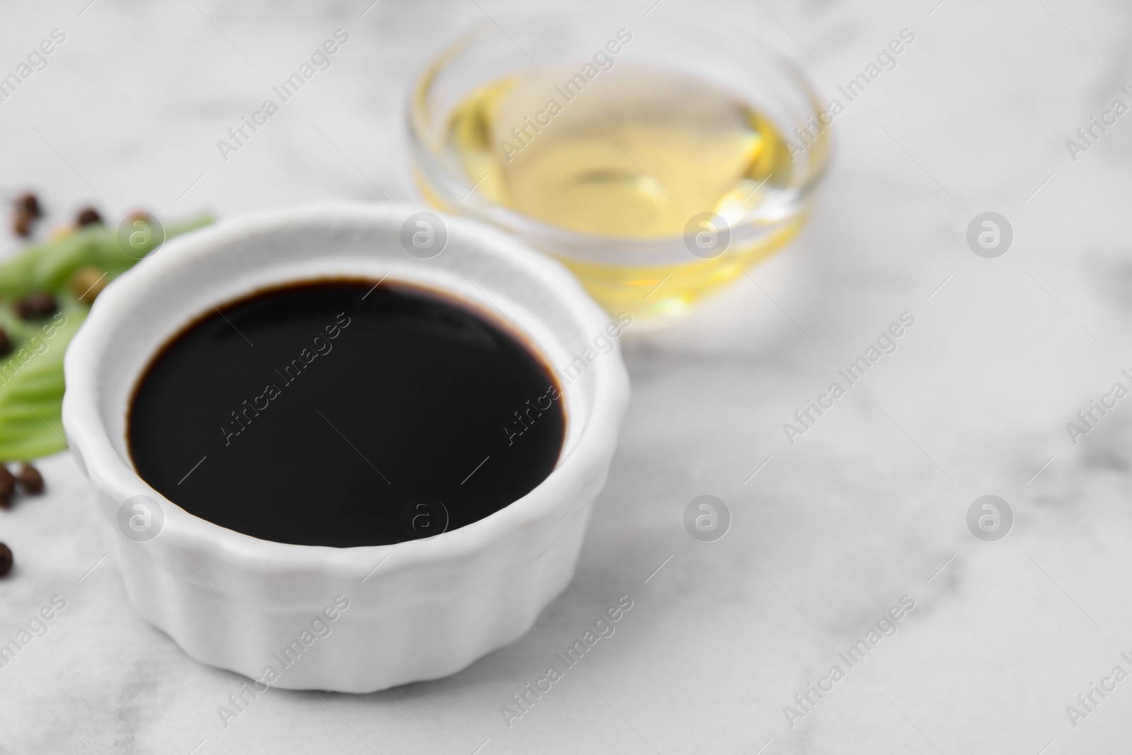 Photo of Bowl with balsamic vinegar on white table, closeup. Space for text