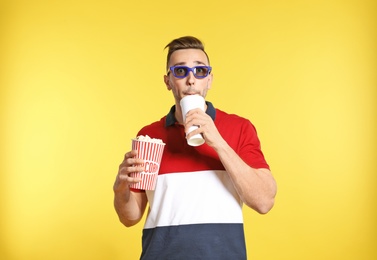 Photo of Emotional man with 3D glasses, popcorn and beverage during cinema show on color background