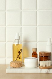 Photo of Different bath accessories and personal care products on wooden table near white tiled wall, space for text
