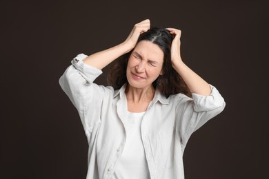 Photo of Mature woman suffering from headache on dark brown background