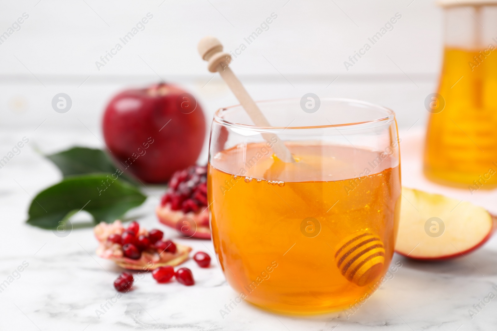 Photo of Honey, apples and pomegranate on white marble table, closeup. Rosh Hashanah holiday