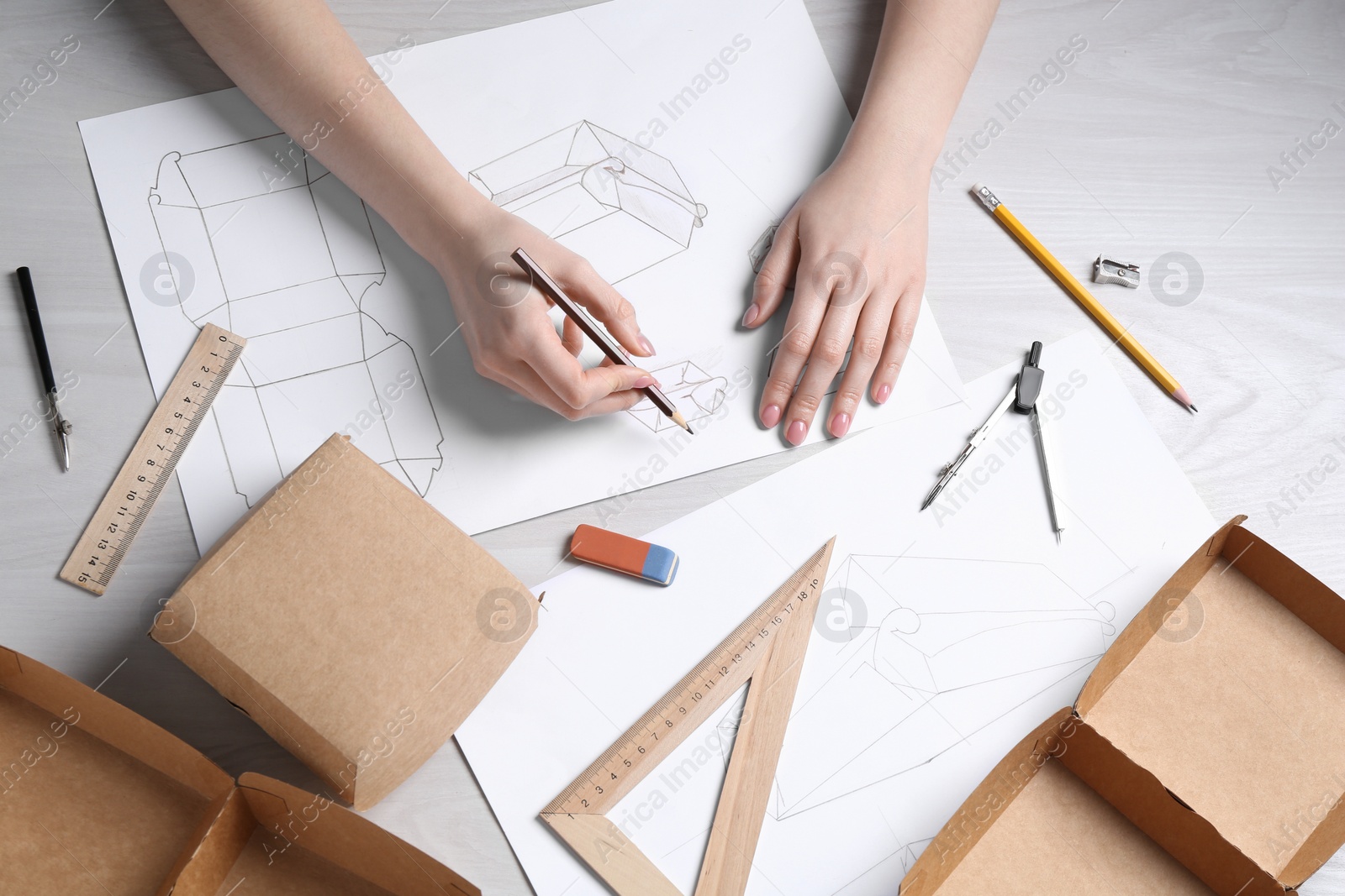 Photo of Woman creating packaging design at light wooden table, top view