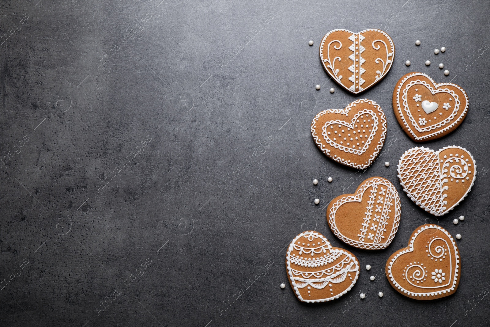 Photo of Tasty heart shaped gingerbread cookies on black table, flat lay. Space for text