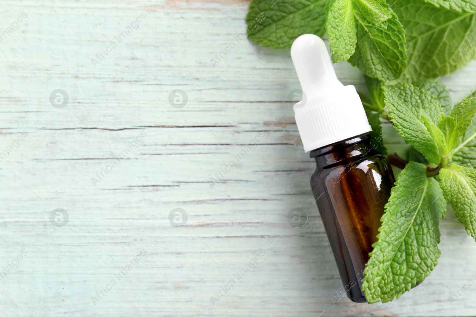 Photo of Bottle of essential oil and mint leaves  on wooden table