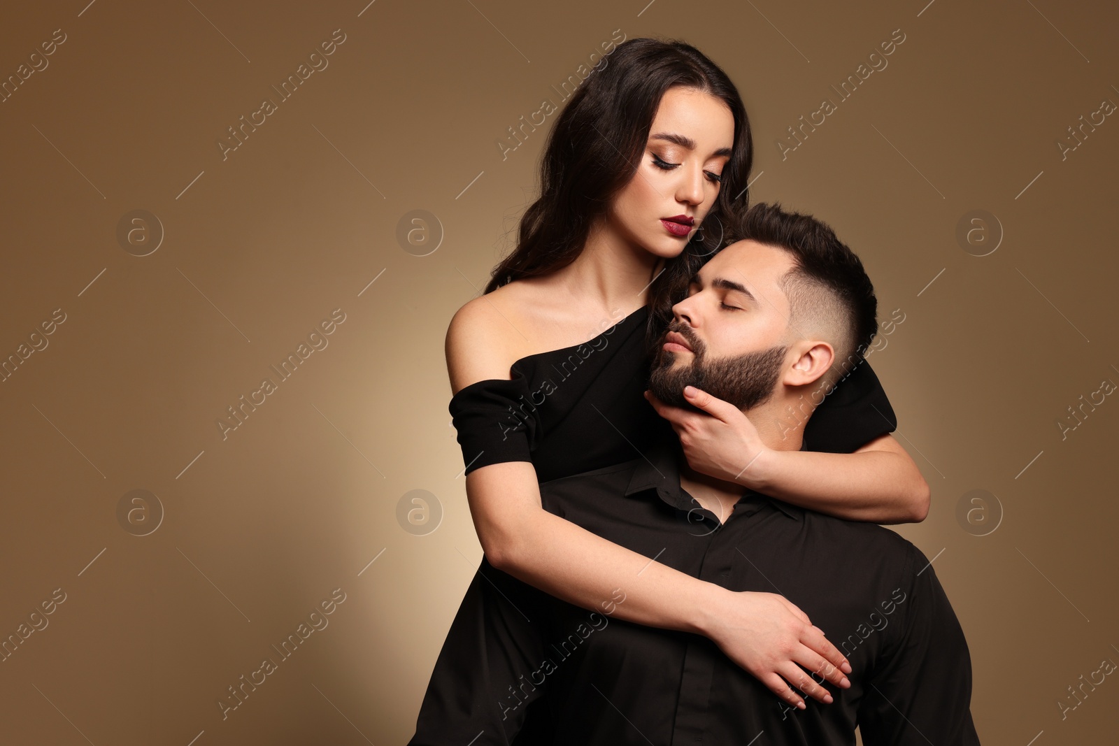 Photo of Handsome bearded man with sexy lady on light brown background. Space for text