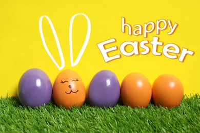 Image of Happy Easter. One egg with drawn face and ears as bunny among others on green grass against yellow background