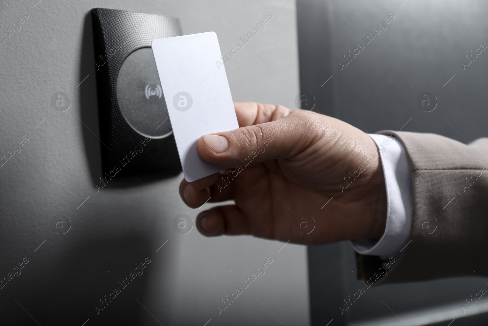 Photo of Man opening magnetic door lock with key card, closeup. Home security