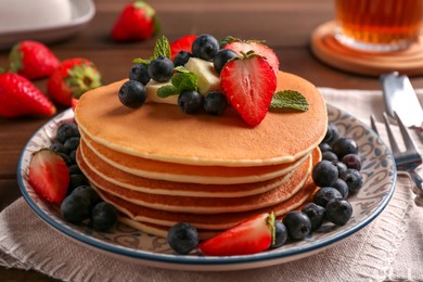 Photo of Delicious pancakes with fresh berries and butter on table, closeup